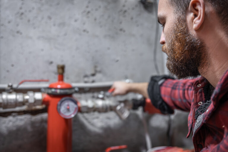 The man looks at the expansion tank, faucet, pipes, valve, pressure meter, copy space.